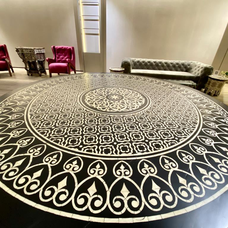 Decorative round rug with intricate mother of pearl patterns in a room with furniture.