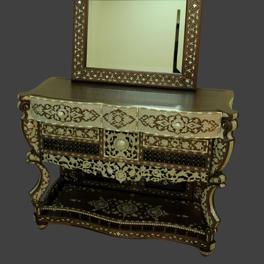 Decorative console table with intricate carvings and a large mirror above it.