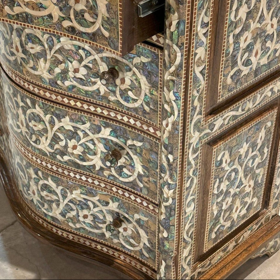 Decorative wooden cabinet with intricate inlay patterns on a marble floor.