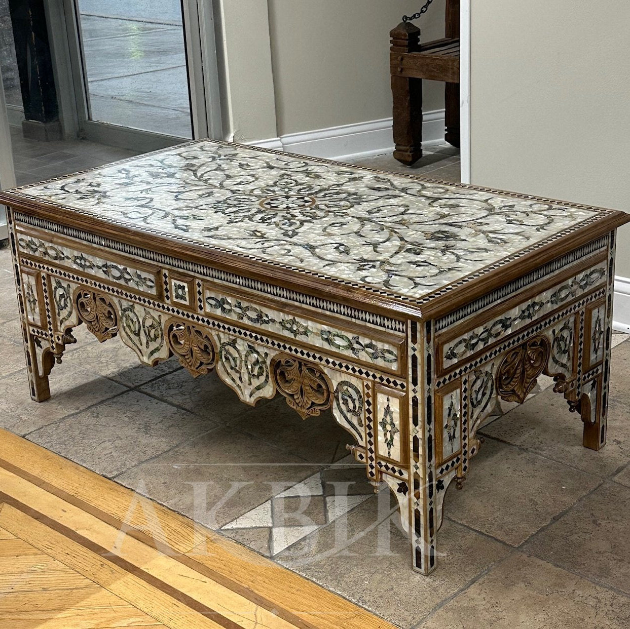 Decorative wooden table with intricate carvings on a tiled floor.