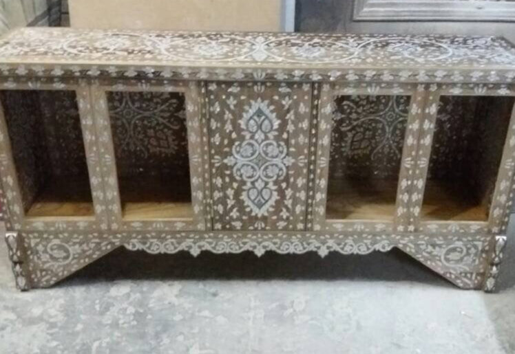 Decorative wooden cabinet with intricate carvings on a concrete floor.