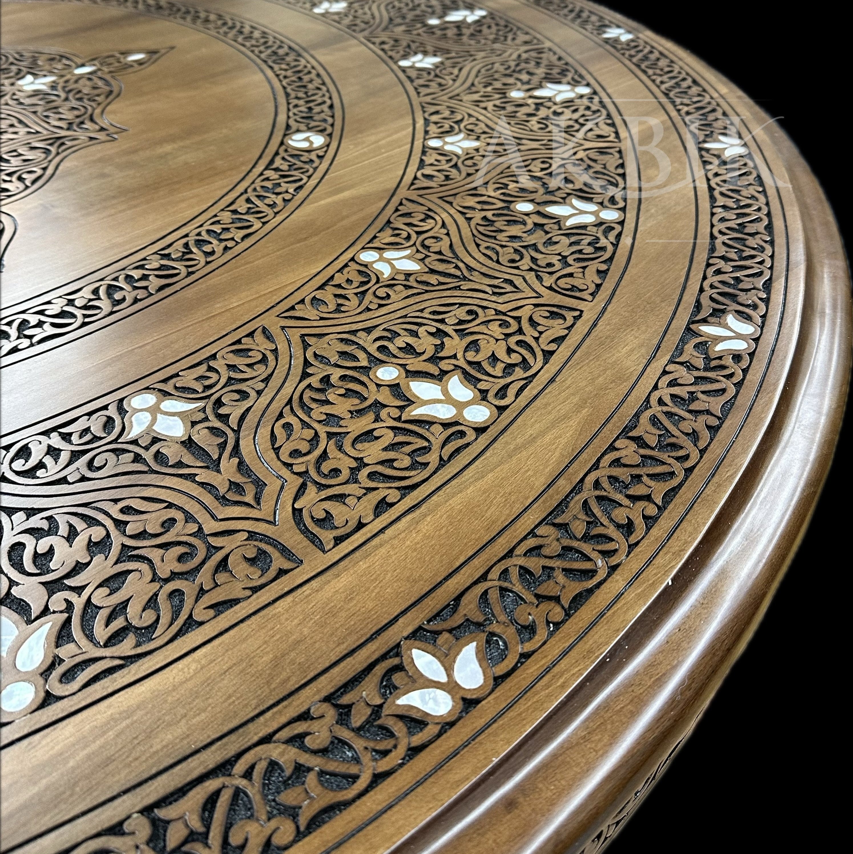 Round wooden table with intricate carvings on a black background