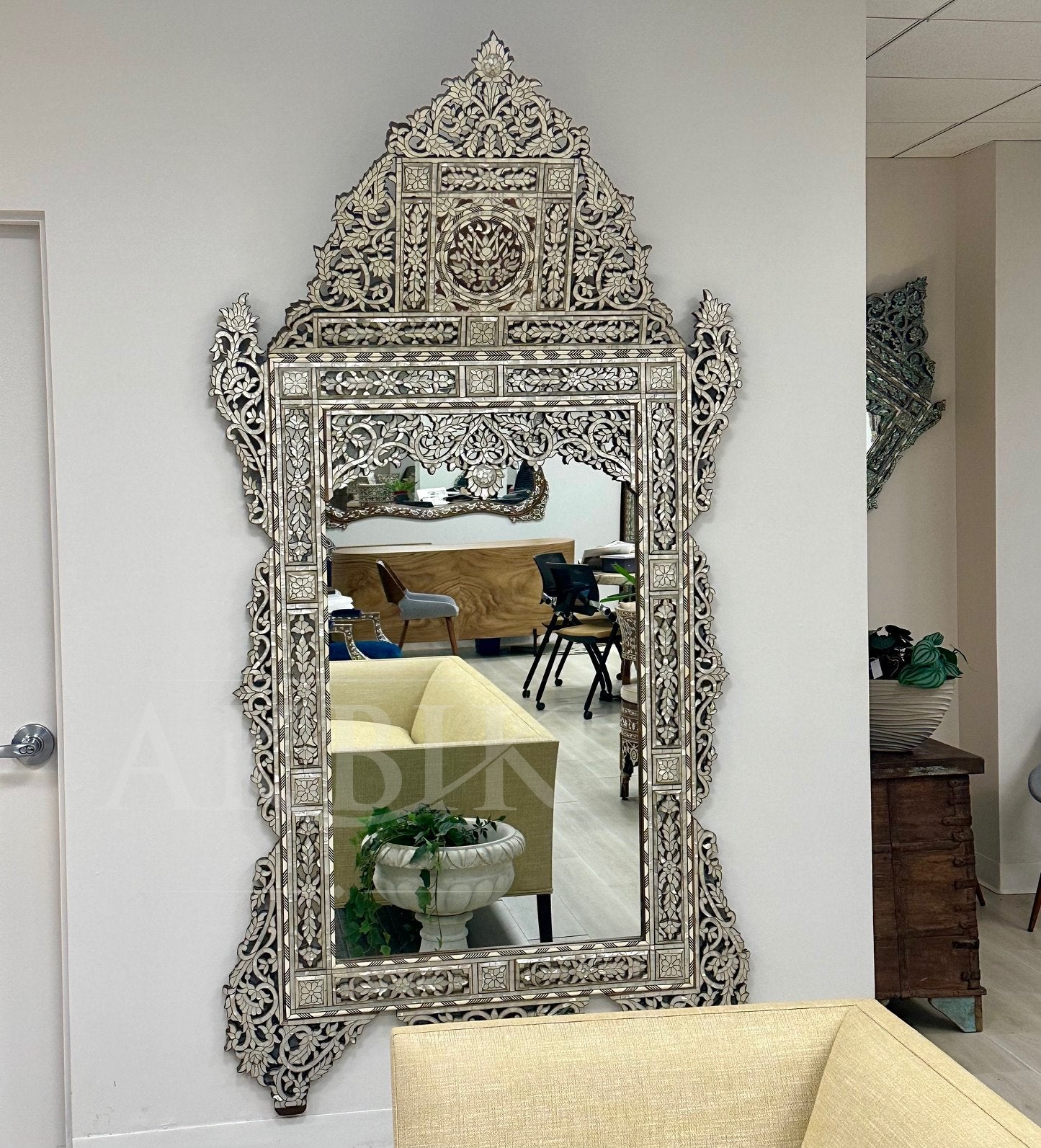 Decorative wall mirror with intricate carvings in a room setting.