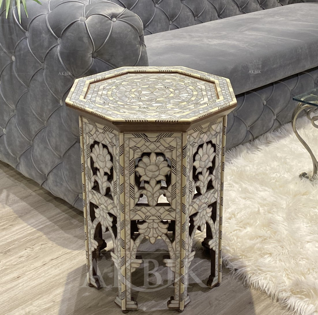 Decorative octagonal side table with intricate carvings in a room setting.