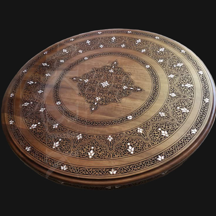 Decorative wooden round panel with intricate carvings on a light-colored wall.