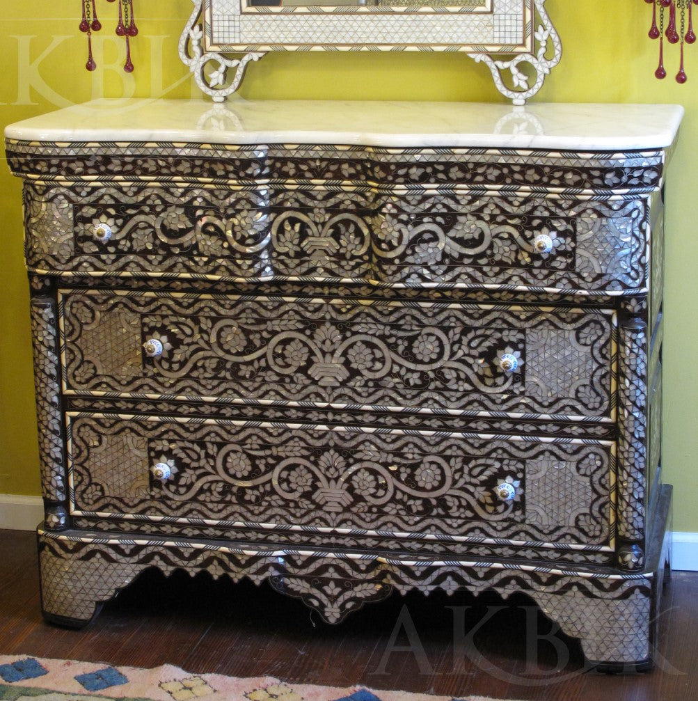 Decorative chest of drawers with intricate patterns against a yellow wall.