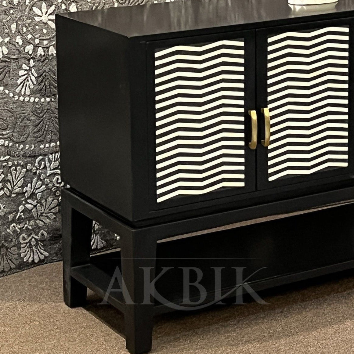 A black sideboard with a geometric chevron pattern on the front, featuring an inlay design and gold-colored handles.